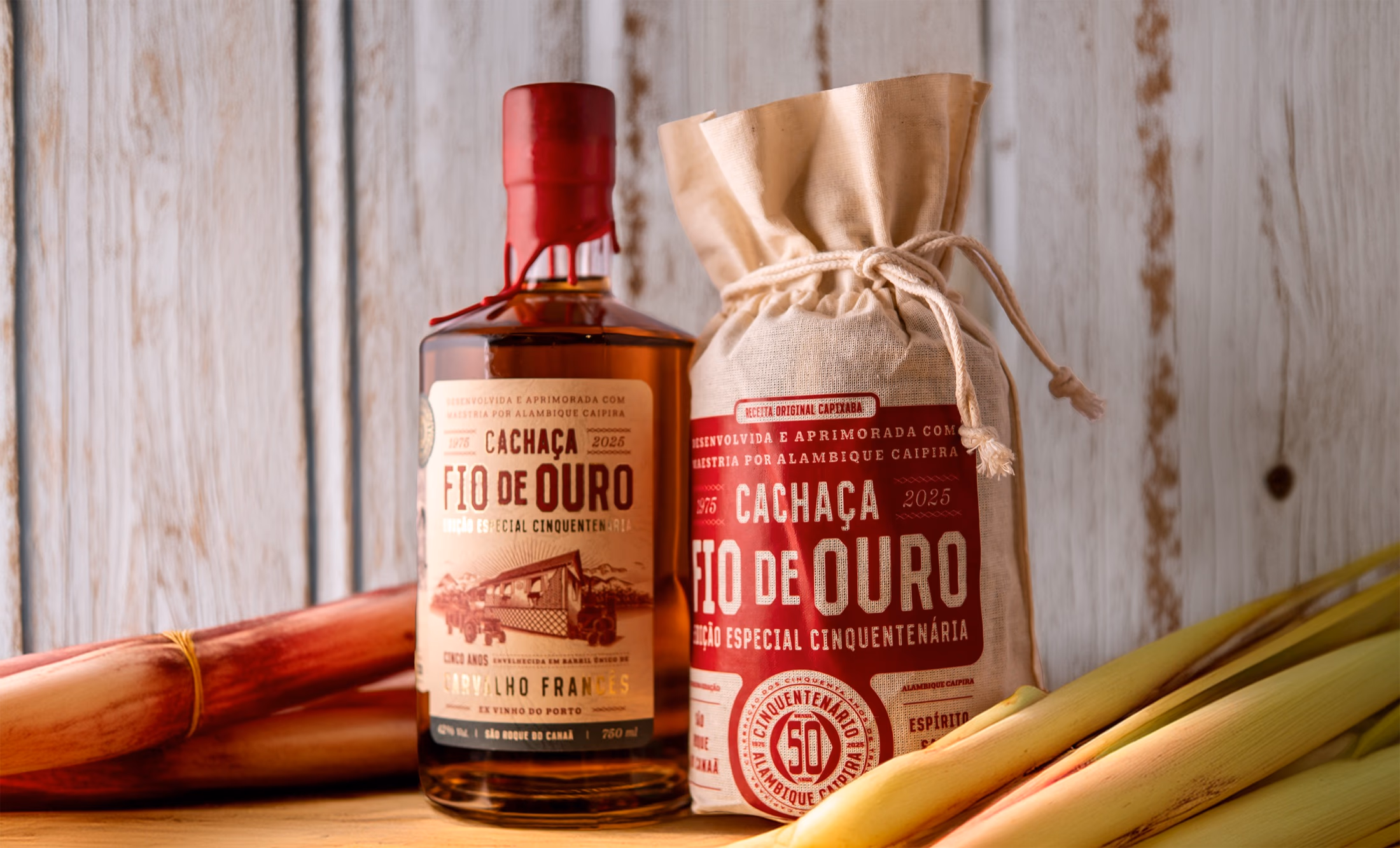 Garrafa da Cachaça Cinquentenária ao lado do saco de estopa e de canas de açúcar