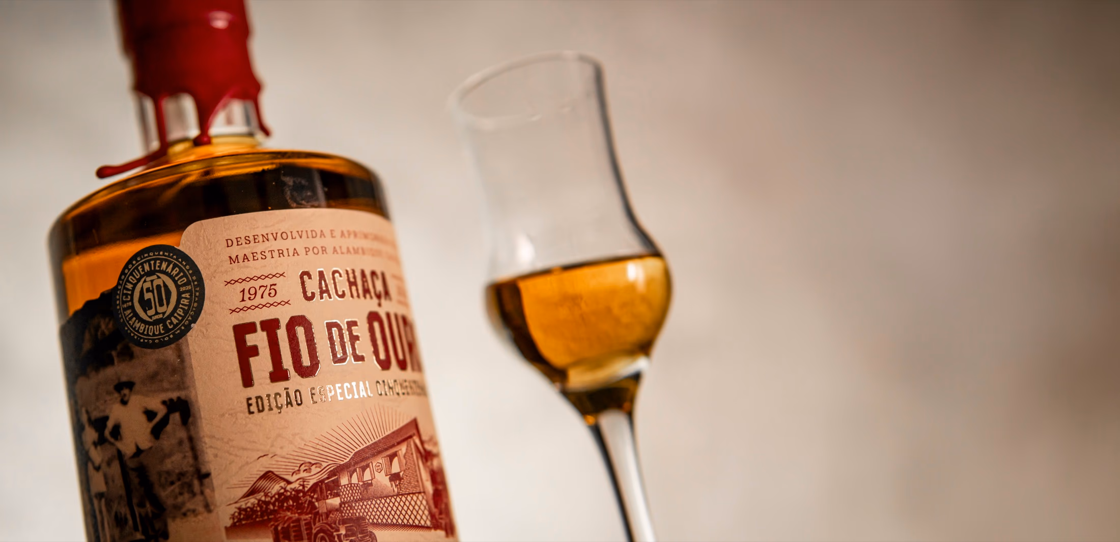 Garrafa da Cachaça Cinquentenária com a taça de degustação, em luz baixa e atmosférica