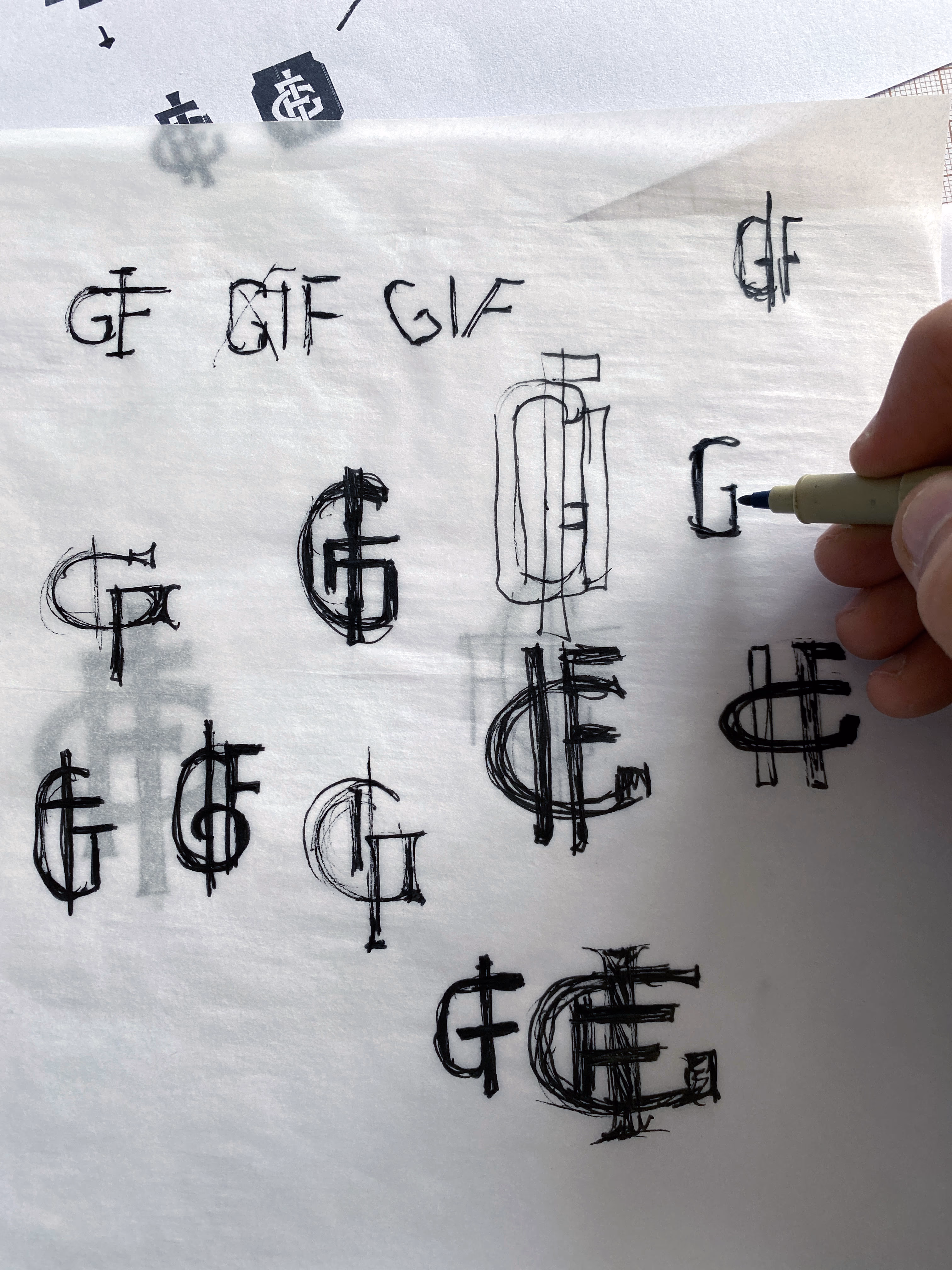Hand-drawn lettering studies of the GIF monogram for General Iron Fittings on tracing paper